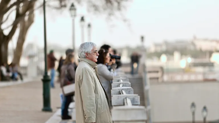 An older man looking our over a bridge in a city.