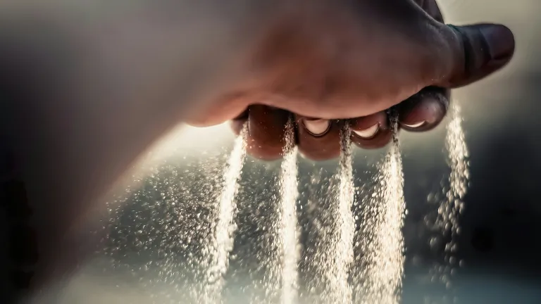 Sand falling from a person's hand.