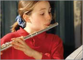 A young girls playing a flute.